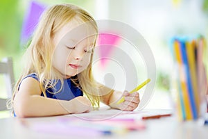 Small girl drawing with colorful pencils at home. Creative kid doing crafts. Education and distance learning for kids.