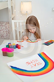 Small girl drew rainbow and poster stay home.
