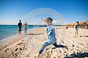 A small girl with family running outdoors on sand beach, having fun.