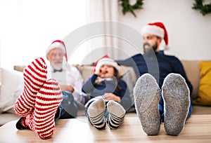 A small girl with father and grandfather sitting on a sofa at Christmas time.