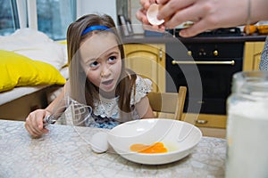 Small girl going to beat the dough for pancakes