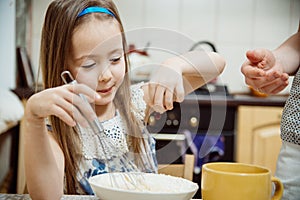 Small girl going to beat the dough for pancakes