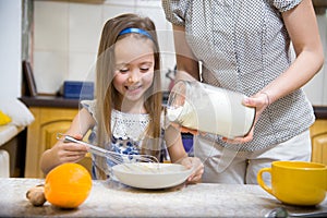 Small girl going to beat the dough for pancakes