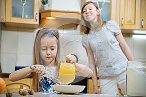 Small girl going to beat the dough for pancakes