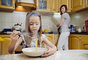 Small girl going to beat the dough for pancakes