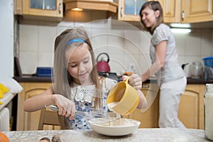 Small girl going to beat the dough for pancakes