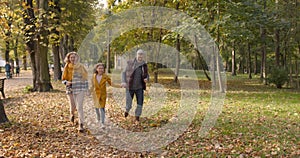 Small girl with grandparents on a walk in autumn forest