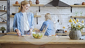 A small girl helps her mom setting the table at home. Girls getting ready for dinner. 4K