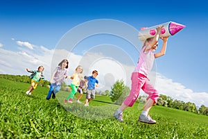 Small girl holding rocket carton toy and kids run