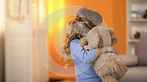 Small girl hugging teddy bear, problems with socialization, lack of friends