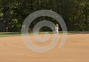 Small girl kicking up dust on a smoothly raked baseball infield photo