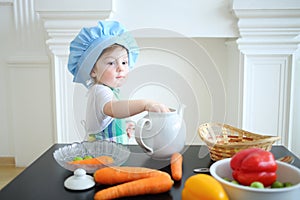 Small girl in kitchen apron and cap standing at photo
