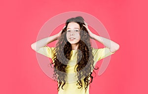 Small girl with long curly hair. fashion model kid has brunette hairstyle. hairdresser for child. shampoo cosmetic for