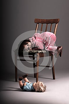 Small girl lying on chair and thinking of doll on floor