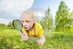 Small girl with magnifier looking through glass