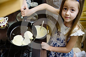 Small girl making pancakes. Mom teach daughter to cook
