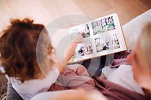 A small girl with mother and grandmother at home, looking at photographs.