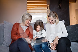 A small girl with mother and grandmother at home.