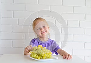 Small girl offers a bunch of grapes