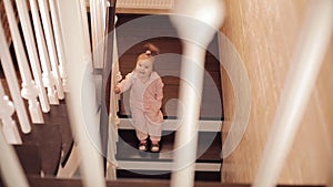 Small girl in pink pyjama sitting on stairs and playing