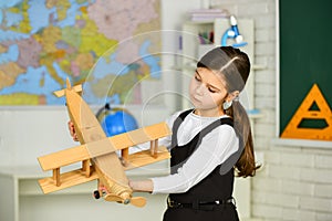 Small girl play with toy airplane. Child pilot aviator with airplane dreams. retro wooden toy in modern education. fly