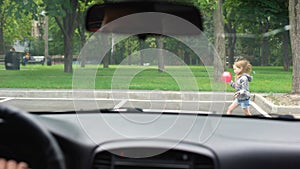 Small girl playing with ball on parking lot, car driver braking sharply, risk