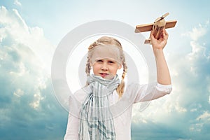 Small girl playing with a toy airplane against the blue sky