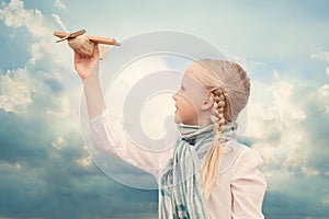 Small girl playing with a toy airplane against the blue sky