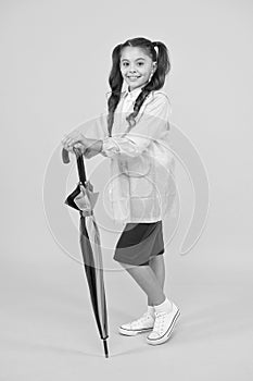 Small girl in raincoat with umbrella. schoolgirl waterproof raincoat. in good mood. feel protected and happy. accessory