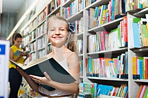 Small girl in school age standing with open book