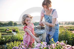 Small girl with senior grandmother gardening in garden center.