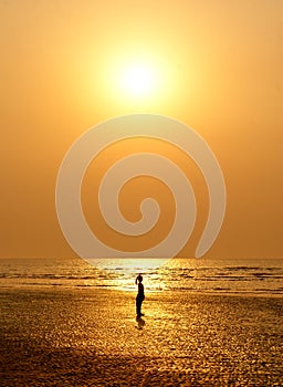 A small girl silhouetted against sun set