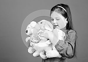 Small girl smiling face with toys. Happy childhood. Little girl play with soft toy teddy bear. Lot of toys in her hands