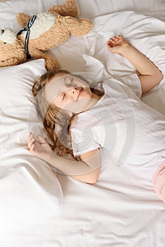 Small girl stretches in bed in the morning. Good relaxed morning