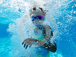 Small girl surrounded by bubbles inside of swimming pool