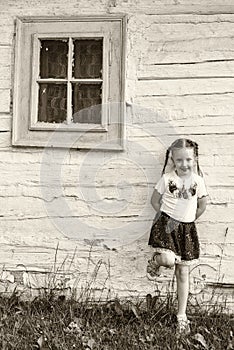 Small girl in traditional skirt posing in traditional village with wooden cottages