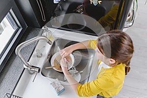 Small girl washing dishes at home