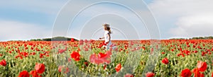 Small girl in white dress running in poppies