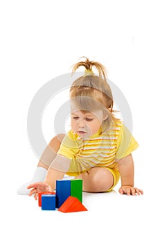 Small girl in yellow build toy pyramid