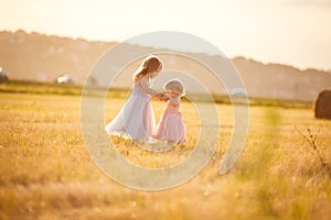 Small girls holding hands stand on sloping field