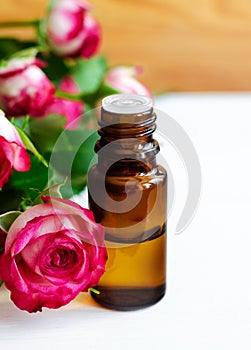 Small glass bottle with essential rose oil. Aromatherapy, spa and herbal medicine ingredients.