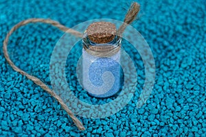 Small glass bottle with sand on blue stones
