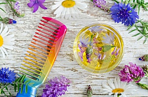 Small glass bowl with aroma cosmetic oil with flowers extracts and hair comb. Ingredients of natural cosmetic.