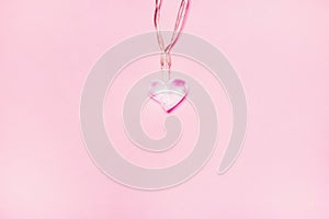 Small glass heart on soft pink background. Valentine& x27;s day symbol. Decorative element. Festive Valentine card