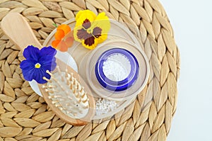 Small glass jar with epsom bath salts foot soak, exfoliation scrub and wooden hairbrush. Natural hair care concept. Top view
