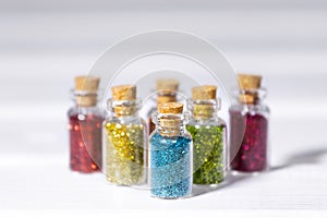 Small Glass jars with Colorful glitters for nail art and makeup on white background, Copyspace