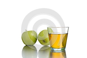 Small glass with juice in front of green apples