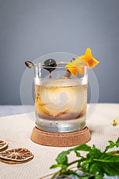 a small glass of an old fashioned drink with orange peel