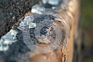 Small glass shards lying on a rusty peeling metal pipe. Shattered, broken glass fragments. Selective focus. Blurred background