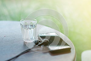 A small glass of water filled with water and a phone placed on the table